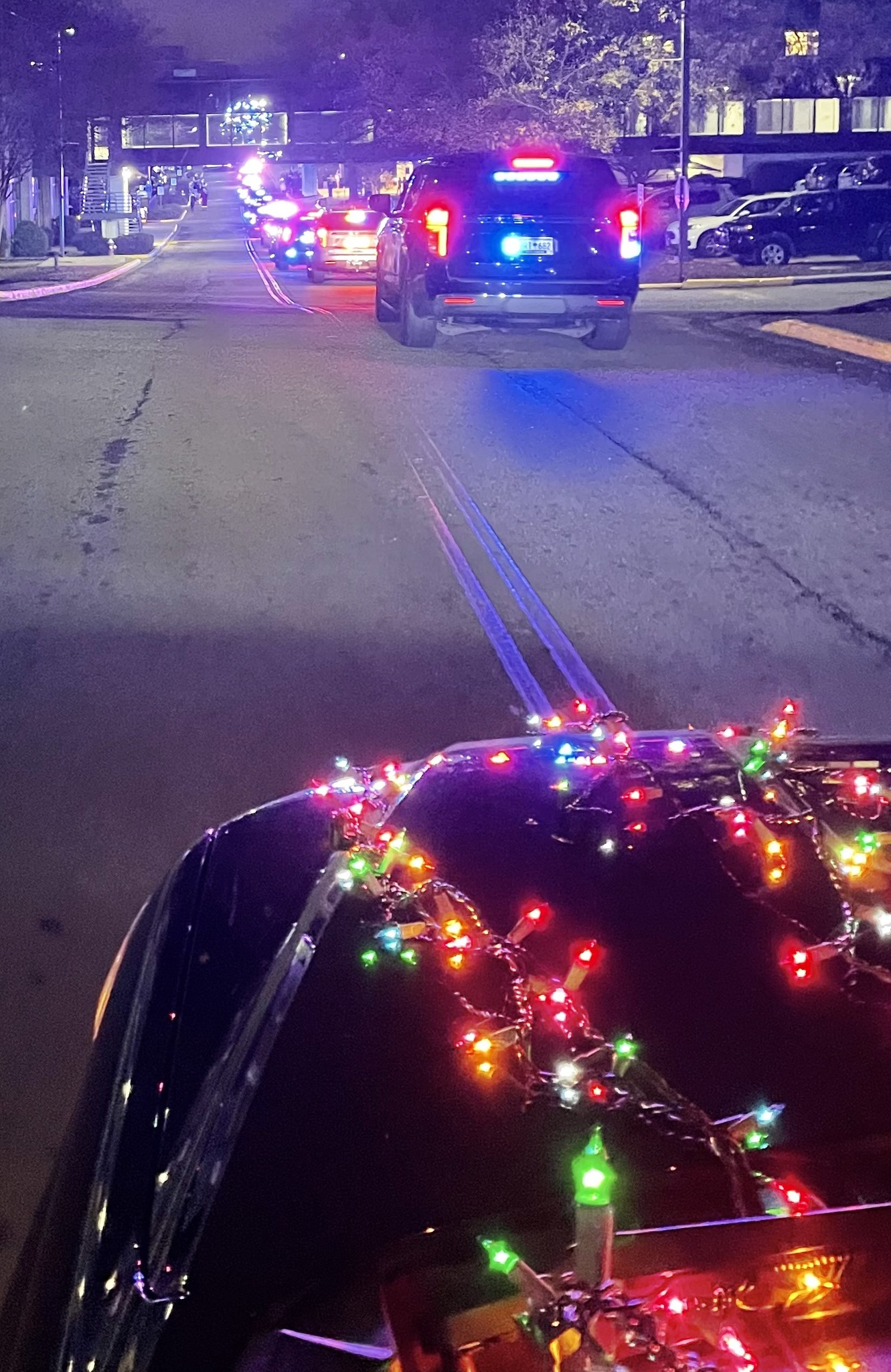 Law enforcement vehicles driving down the road with Christmas lights