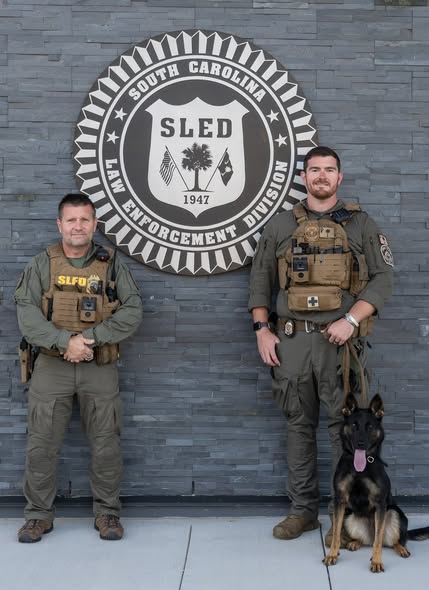 K9 Timber's handler Agent Corey Jager (Right of  SLED Seal) and Senior Special Agent Douglas Wannemacher (Left of SLED Seal) 